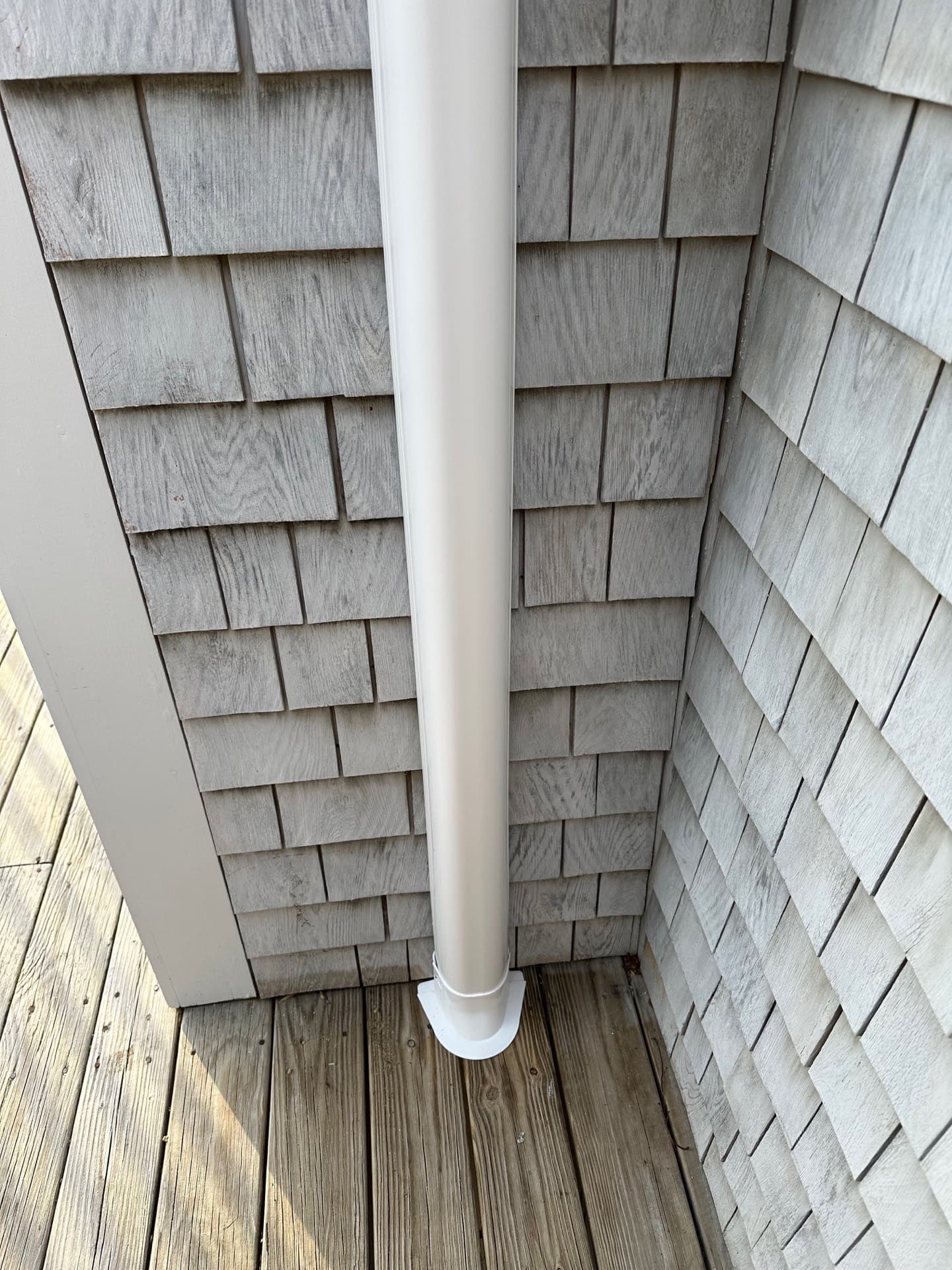 Line-set cover run down the corner of a cedar-shingled exterior wall to the deck