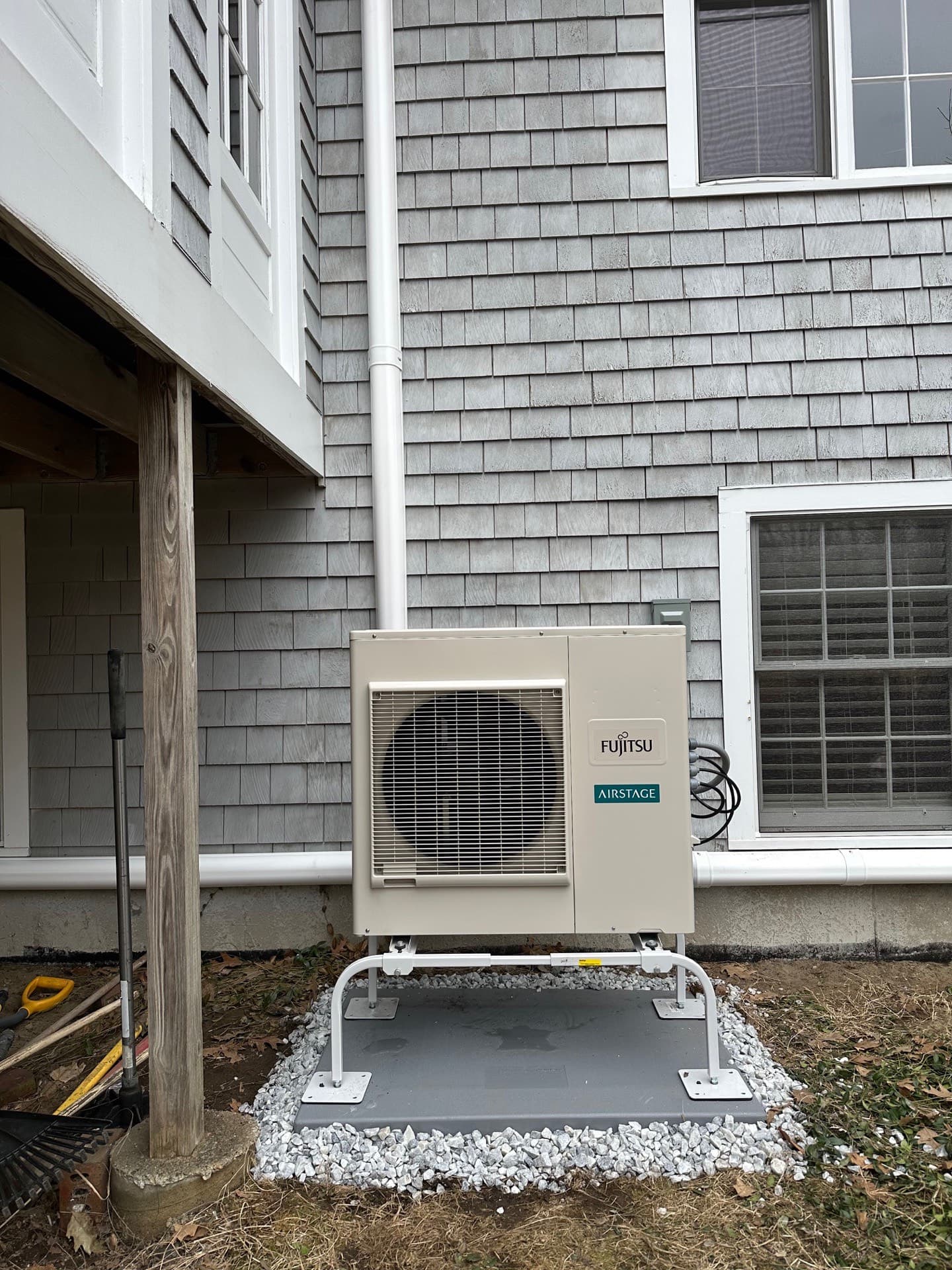 Fujitsu mini-split outdoor unit mounted on a stand over a gravel pad