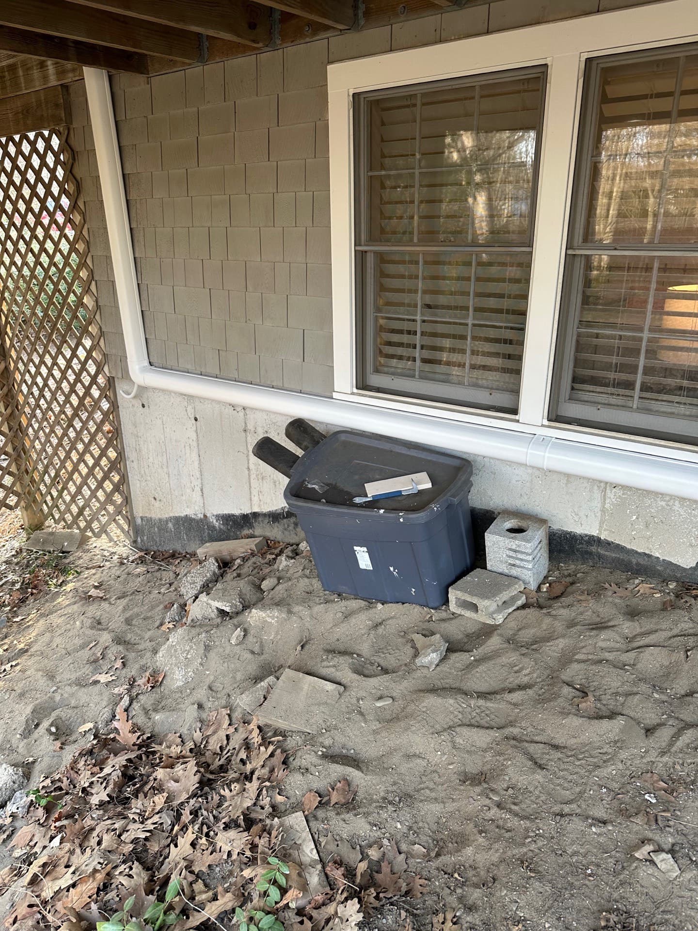 Line-set run along a foundation wall in the crawl space beneath a deck