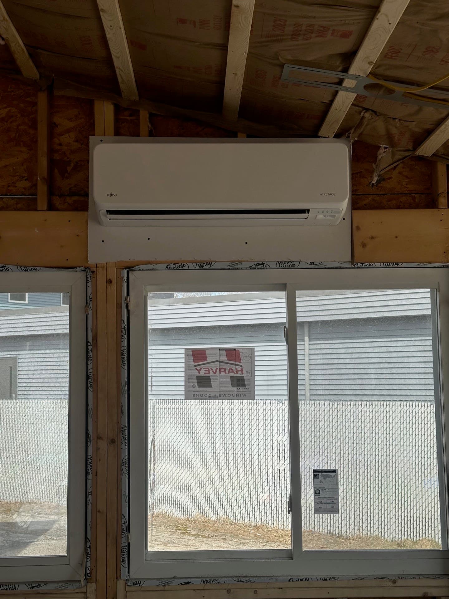 Wall-mounted mini-split head installed in an unfinished space with exposed framing