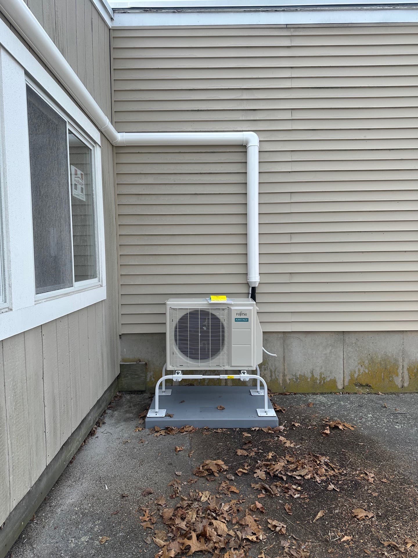 Mini-split condenser on a stand with the line-set cover running up the wall
