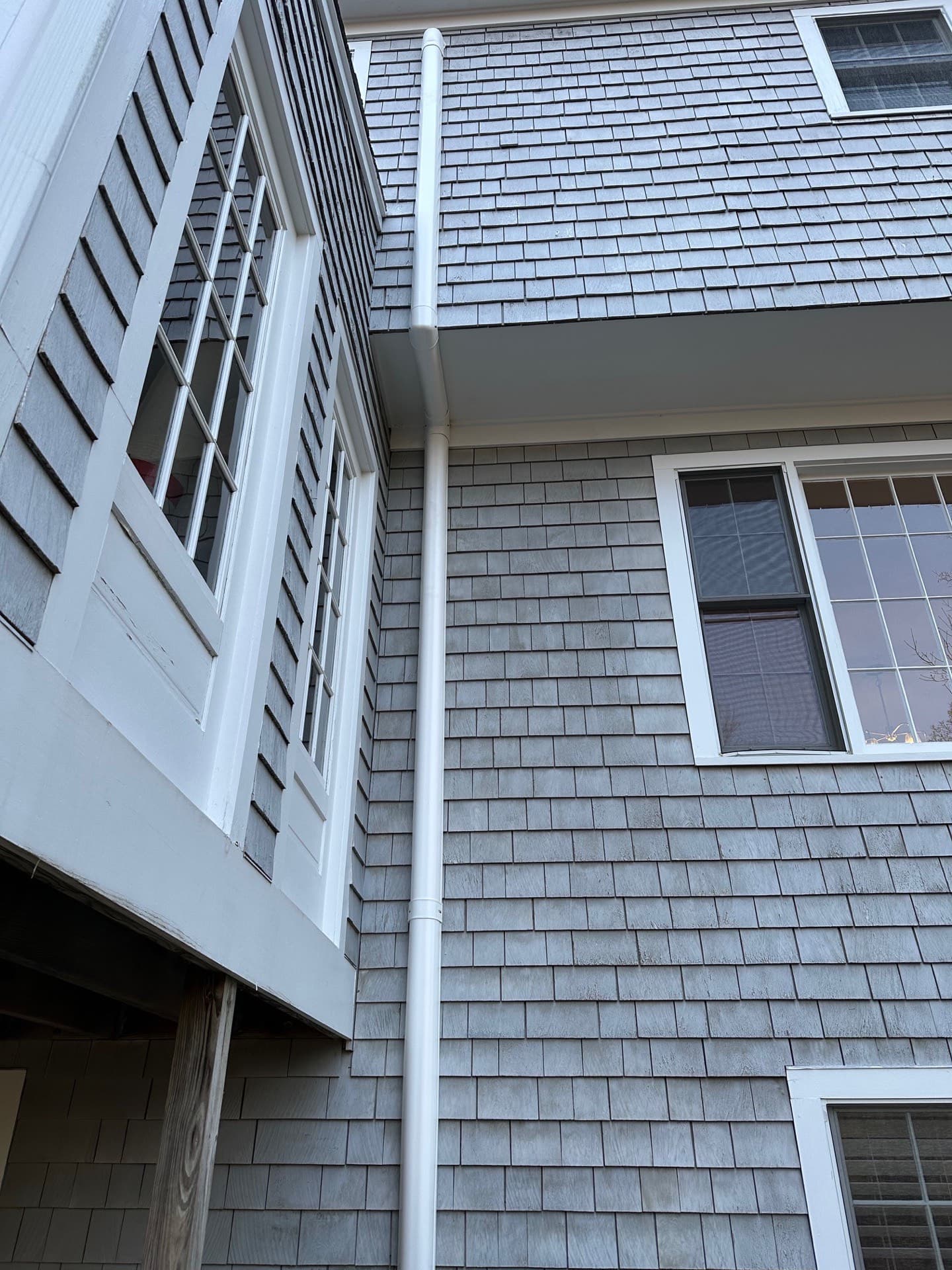 Line-set routed along the eaves of a shingled home past a bay window