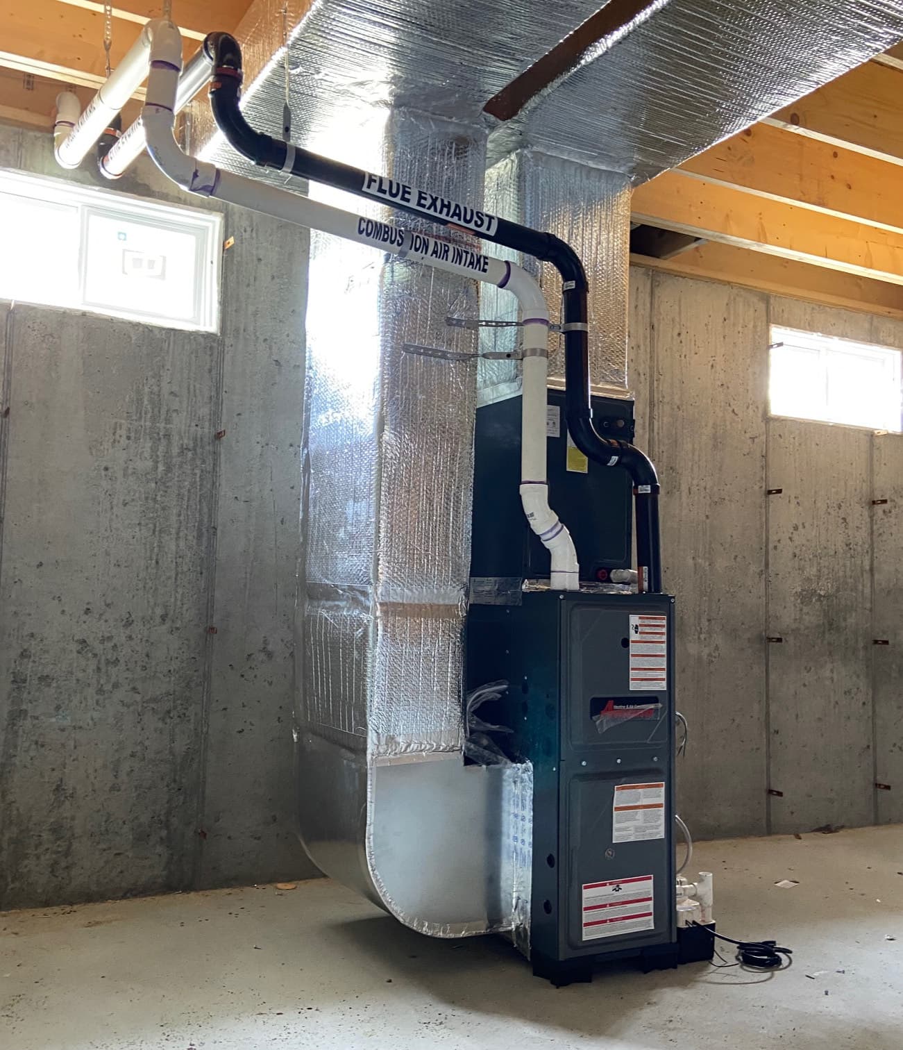Newly installed high-efficiency furnace and insulated ductwork in a basement